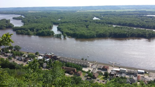 Aerial view of a river winding through lush greenery, with a small town visible along the riverbank.