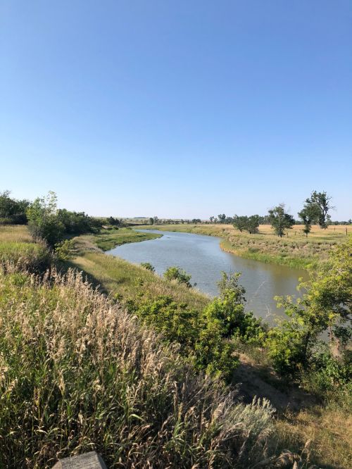 A serene river winding through lush greenery under a clear blue sky.