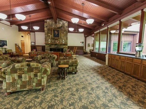Cozy lounge area with patterned sofas, a stone fireplace, large windows, and wooden accents.