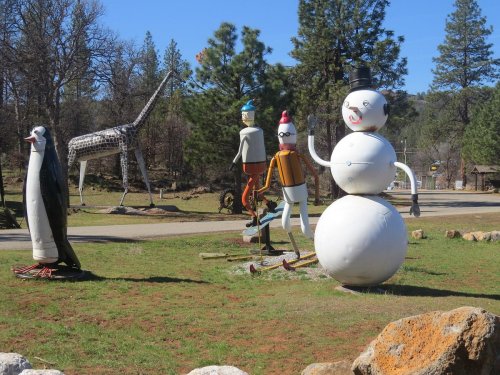 A whimsical outdoor scene featuring large, colorful sculptures of a penguin, giraffe, snowman, and other characters.