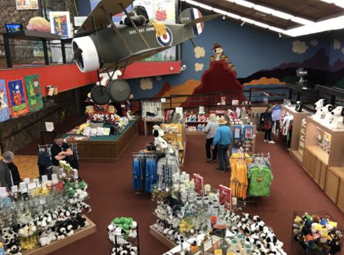 A colorful gift shop filled with plush toys, souvenirs, and a model airplane hanging from the ceiling.