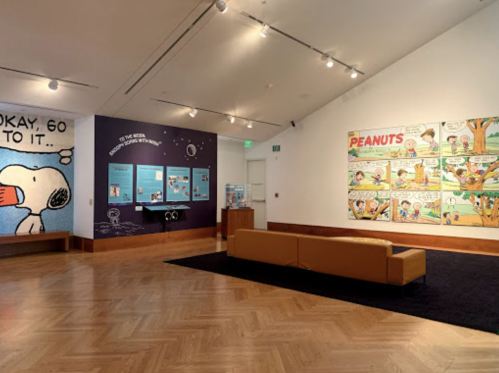 A gallery featuring Peanuts artwork, a Snoopy mural, and an information display in a bright, modern space.