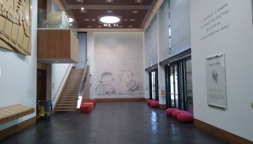 Interior of a modern building featuring a large mural, stairs, and colorful seating along the wall.