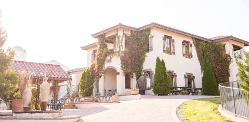 A charming two-story building with ivy-covered walls, surrounded by greenery and outdoor seating areas.