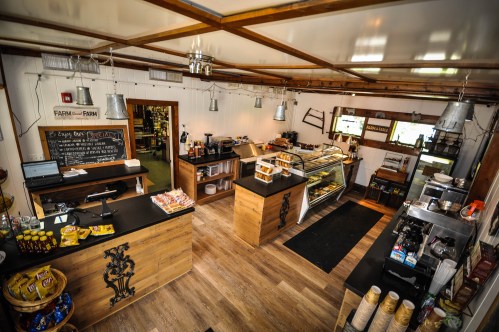 Cozy café interior with wooden counters, display cases, and a welcoming atmosphere, featuring snacks and coffee equipment.