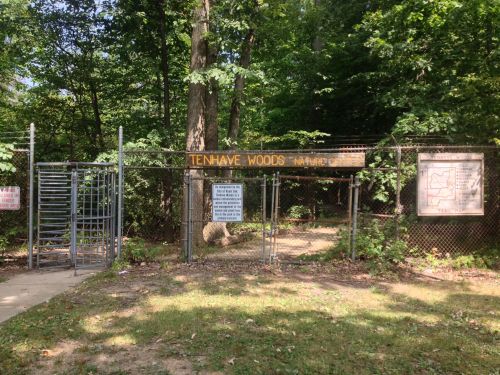 Entrance to Tenhave Woods Nature Center, featuring a gated entry and surrounding greenery.