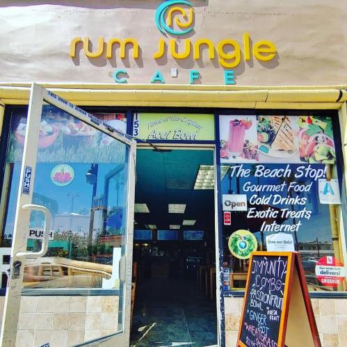 Entrance of Rum Jungle Cafe featuring colorful signage, a menu display, and a welcoming atmosphere.