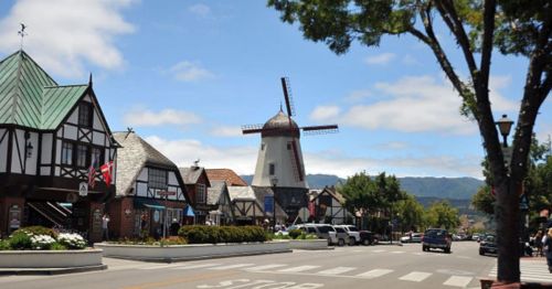 A charming street scene featuring a windmill and quaint buildings with a clear blue sky in the background.
