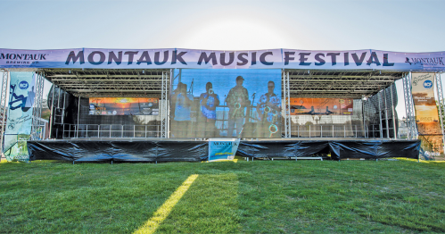 A large outdoor stage set up for the Montauk Music Festival, with banners and a grassy area in front.