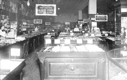 A vintage store interior filled with merchandise, featuring wooden displays and signs indicating price limits.