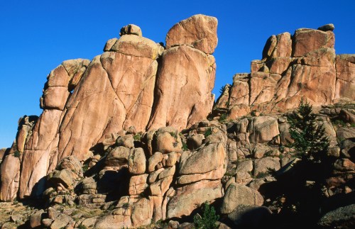 Rock formations with large boulders against a clear blue sky, showcasing natural textures and shapes.