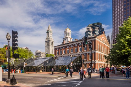 Historic building with a clock tower, bustling street, and clear blue sky in an urban setting.