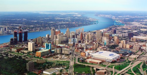 Aerial view of a city skyline with tall buildings, a river, and bridges in the background.
