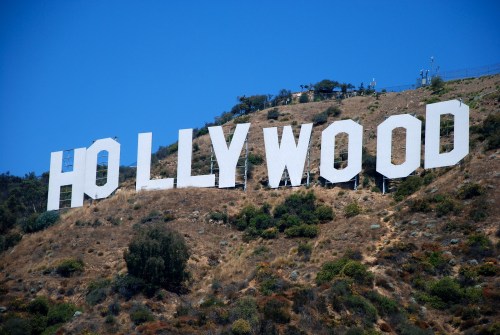 The iconic Hollywood sign on a hillside, surrounded by greenery and a clear blue sky.