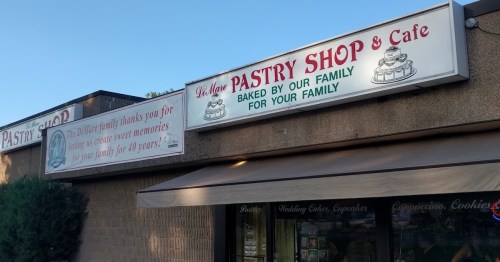 Signage for "It's More Pastry Shop & Cafe," featuring a thank you message from the Wallace family for 40 years of service.