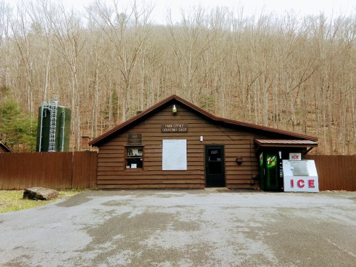 A rustic park office building with a sign, surrounded by bare trees and a small ice vending machine outside.