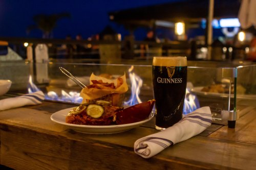 A plate of food with fries and a lobster, alongside a pint of Guinness, set against a cozy evening backdrop.