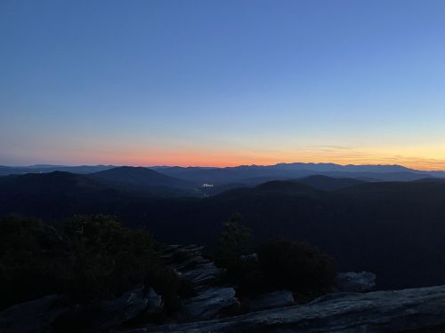 A serene mountain landscape at dusk, with a gradient sky transitioning from blue to orange over distant peaks.
