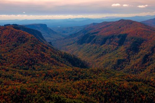 A panoramic view of colorful autumn mountains and valleys under a cloudy sky.