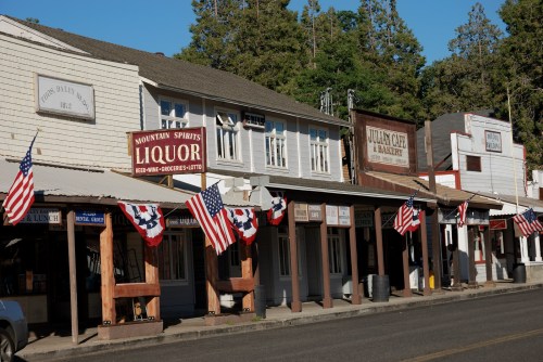 Historic buildings line a street, adorned with American flags, in a quaint town setting.