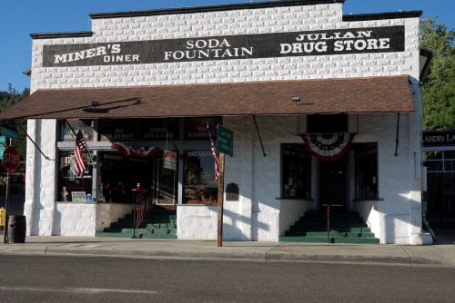 Historic building featuring Miner's Diner and Julian Drug Store, adorned with American flags and a soda fountain.
