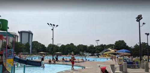 A busy outdoor water park with pools, slides, and people enjoying the sun on a clear day.