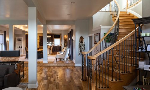 A spacious, modern home interior featuring a staircase, living area, and dining space with wooden floors.