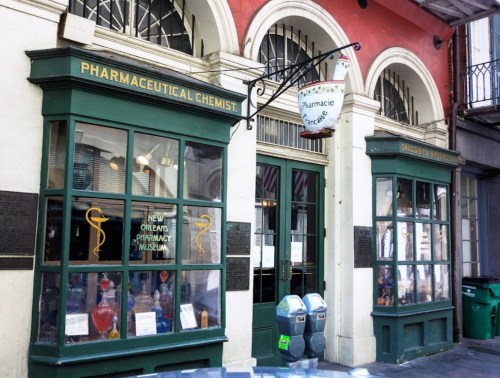 Historic pharmacy building with green windows, showcasing a pharmacy museum sign and vintage decor in New Orleans.
