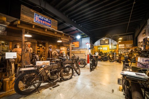 A vintage motorcycle museum featuring various bikes, historical displays, and rustic decor in a well-lit space.