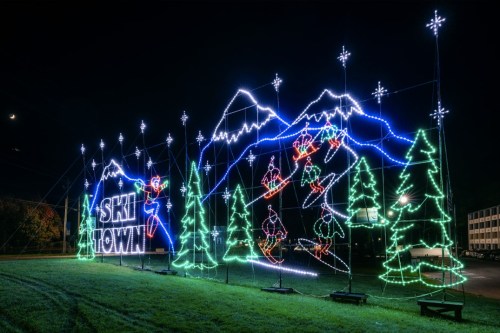Colorful holiday lights display featuring skiers, mountains, and trees, with "SKI TOWN" illuminated in the center.