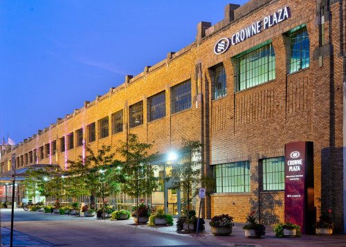 Exterior view of the Crowne Plaza hotel, featuring brick architecture and illuminated landscaping at dusk.