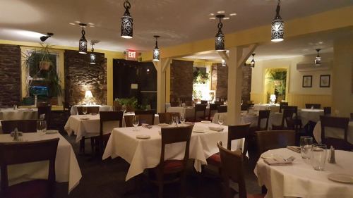 Cozy restaurant interior with stone walls, white tablecloths, and warm lighting from decorative lanterns.