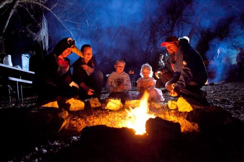 A group of people gathered around a campfire at night, enjoying the warmth and glow of the flames.