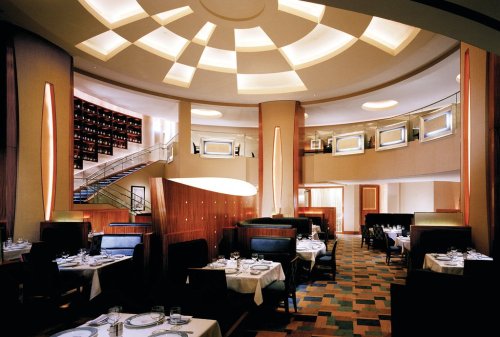 Elegant restaurant interior featuring modern decor, circular ceiling lights, and neatly set tables.