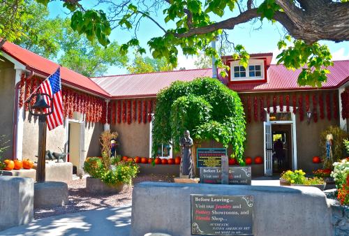 A charming building with red chili decorations, pumpkins, and an American flag, surrounded by greenery and flowers.