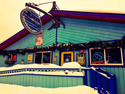 Colorful restaurant exterior with a sign, surrounded by snow and festive decorations.
