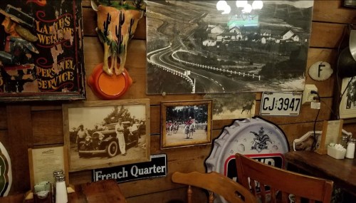 A rustic wall adorned with vintage signs, photographs, and artwork, featuring a scenic road and historical images.
