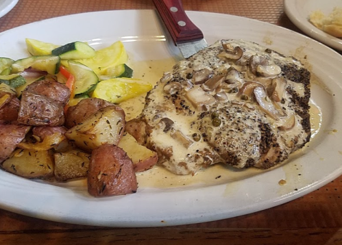 A plate featuring seasoned chicken with creamy mushrooms, roasted potatoes, and sautéed zucchini and squash.