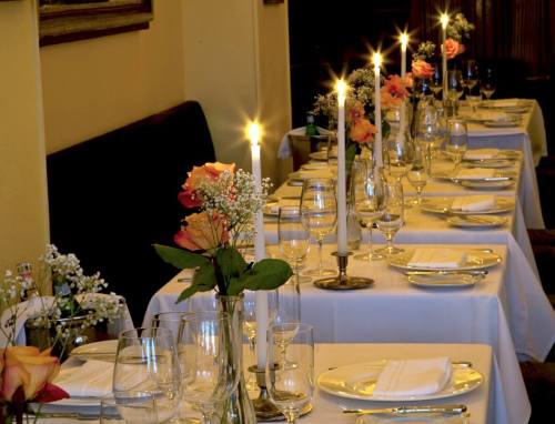 Elegant dining setup with white tablecloths, candles, and floral centerpieces, creating a warm, inviting atmosphere.