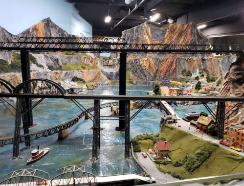 A detailed miniature landscape featuring bridges, mountains, and a river with small buildings and vehicles.