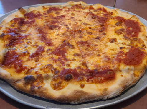 A freshly baked cheese pizza with a golden crust and tomato sauce, sliced into equal pieces on a metal tray.