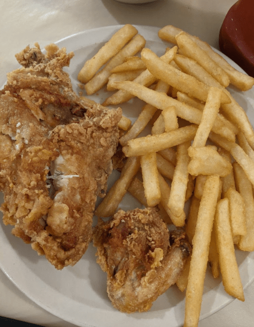 A plate of crispy fried chicken pieces served with golden French fries.