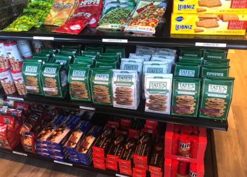A display shelf filled with various snacks, including cookies, crackers, and candies in colorful packaging.