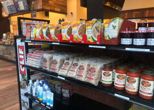 A grocery shelf displaying various packaged foods, sauces, and snacks in a store setting.