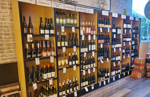 A display of various wine bottles organized on wooden shelves in a store.
