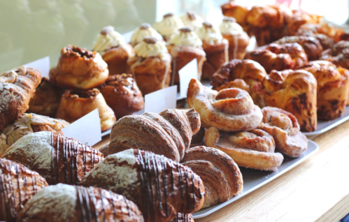A variety of freshly baked pastries, including croissants, cinnamon rolls, and sweet buns, displayed on a table.