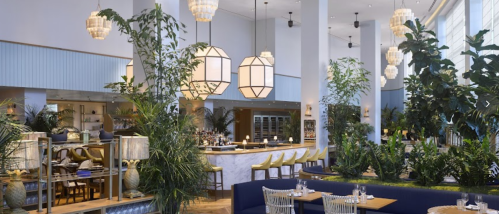 A modern restaurant interior featuring lush greenery, stylish lighting, and a spacious bar area.