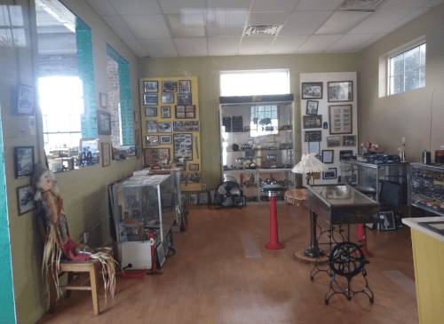 A museum interior featuring display cases, framed photos, and various artifacts on the walls.