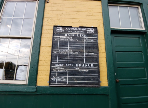 Train schedule board displaying arrival and departure information for the Cowan, Tennessee station.