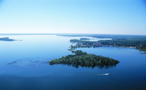 Aerial view of a serene lake with small islands and lush greenery under a clear blue sky.